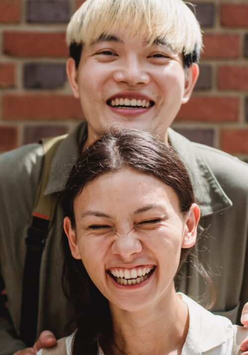 crop happy diverse couple near brick wall on street