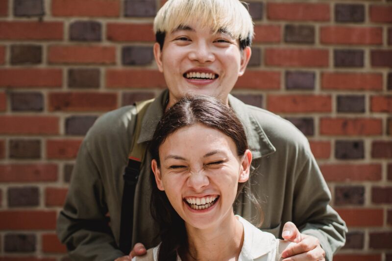 crop happy diverse couple near brick wall on street